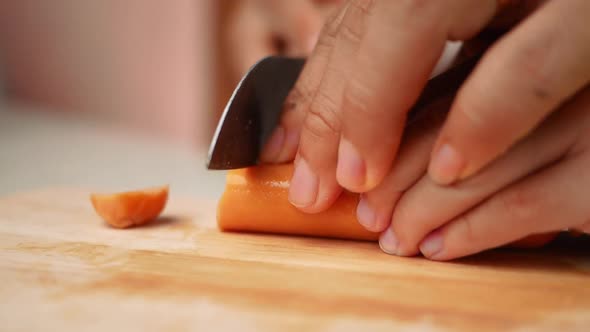 Close up of a knife cuts the sausage into small pieces.