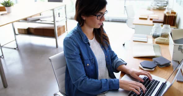 Female executive sitting at desk and using laptop