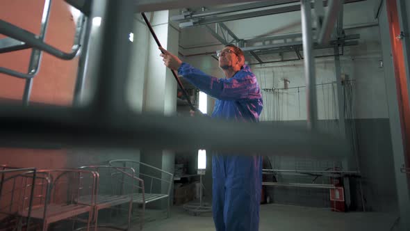 Paint shop worker moves structures for painting to a special spray booth