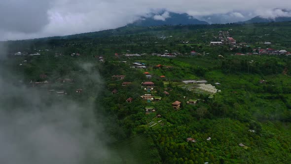 aerial of mountain hotel resort through the fog and rain clouds in Munduk, Bali, Indonesia