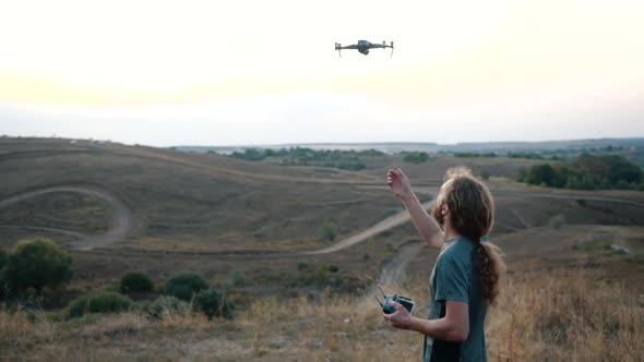 Drone Pilot Puts the Drone in His Hand on a Background of Sunset in Nature. Drone Takes Off From the