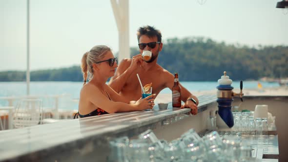 Couple On Bar Counter Relaxing. Lovers On Bar Counter Drinking Cocktails.Guy And Girl  Joyfully