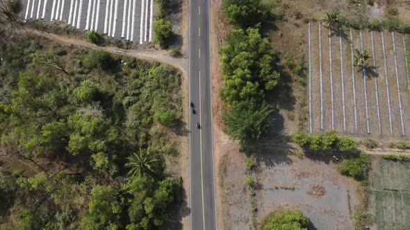 aerial view, drone footage following a speeding motorbike through the savanna forest on the southern