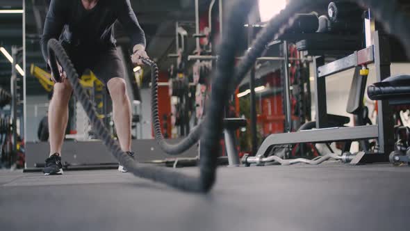 Athletic Man in a Gym Performs Exercises with Battle Ropes Crossfit Endurance Training