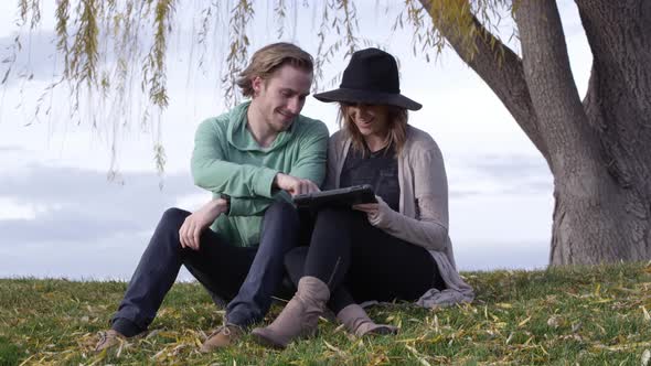 Young man and woman drawing on tablet and laughing