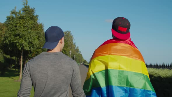 Happy Gay Couple with Rainbow Flag Walking Outdoor