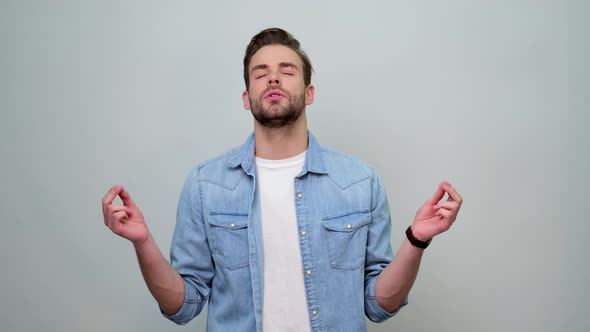 Handsome Calm young european guy relaxing, meditating, calms down, breathes deeply with mudra om