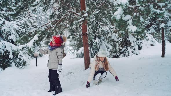 Child at winter in nature. Happy kids playing together with snow, outdoors winter vacation