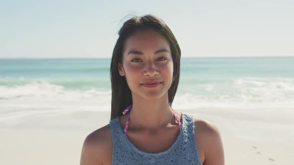 Mixed race woman laughing at beach and looking at the camera