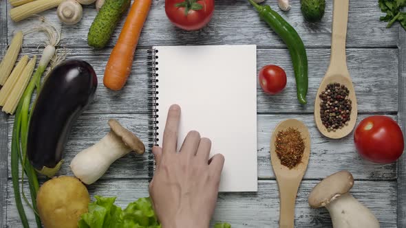 The Cook Reads the Recipe By Swiping His Finger on a White Sheet in a Notebook