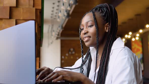 Young African American Woman Using Laptop Computer in Cafe