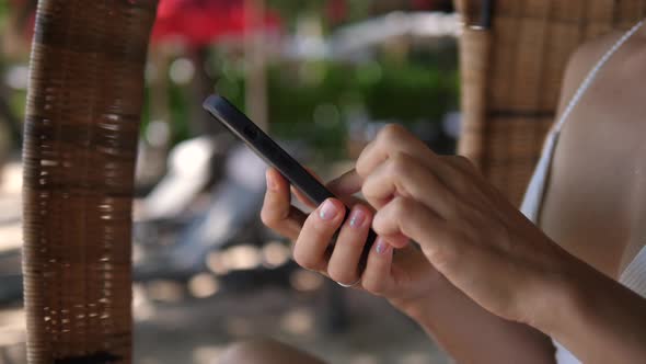 Close Up of Female Hands Using Smartphone While Relaxing on a Beach