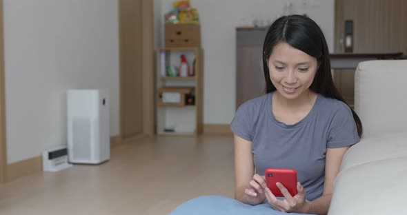 Woman control the robotic vacuum cleaner with cellphone at home