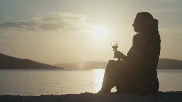 Girl at Sunset By the Sea with a Glass of Wine