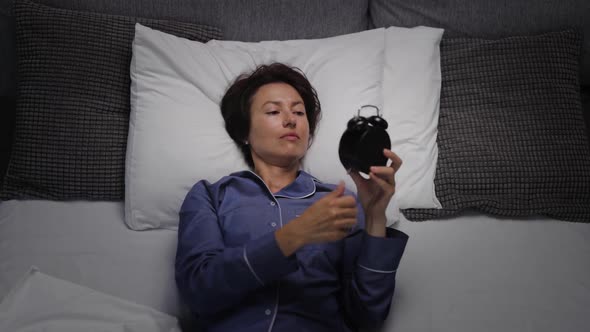 Woman Setting Alarm on Clock