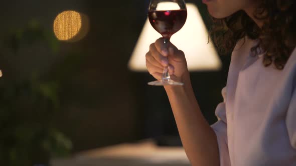 Young Mixed Race Woman Reading Exciting Book and Drinking Red Wine in Cozy Cafe