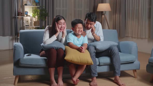 Asian Family, Leisure And People Concept, Father, Mother And Son Watching Scary Movie On Tv At Home