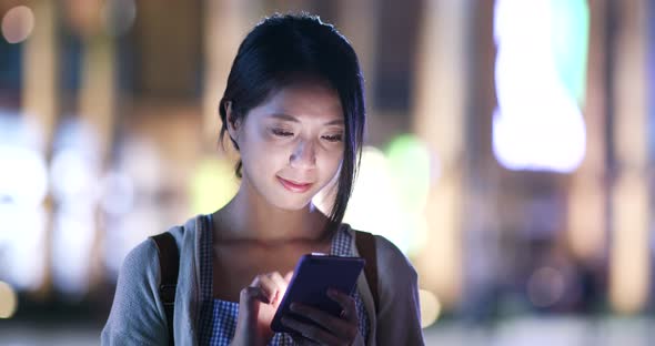 Woman use of mobile phone in city at night