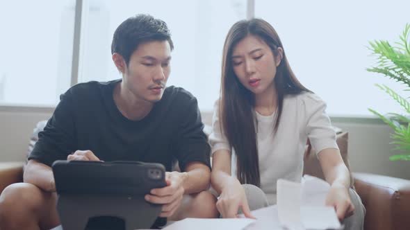 couple checking and calculate financial billing together on sofa involved in financial paperwork