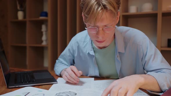 Young Man Searching Through the Dictionary Book and Writing in His Notes