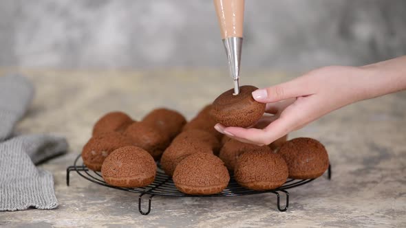 A chef filling a chocolate profiteroles with cream