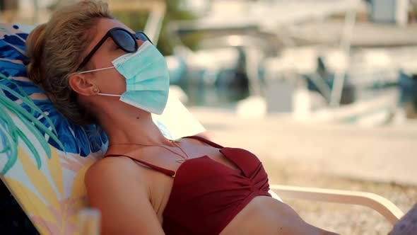 Woman Sunbathing In Protective Mask COVID19 Virus On Vacation Holiday.Woman On Sunbed In Face Mask