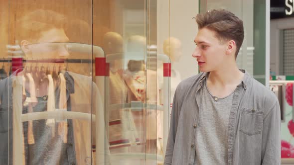 Young Man Examining Clothing on Display of a Store at the Shopping Mall