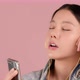 Happy pretty Asian teenager girl listening and sing a song by smartphone on pink background. - VideoHive Item for Sale