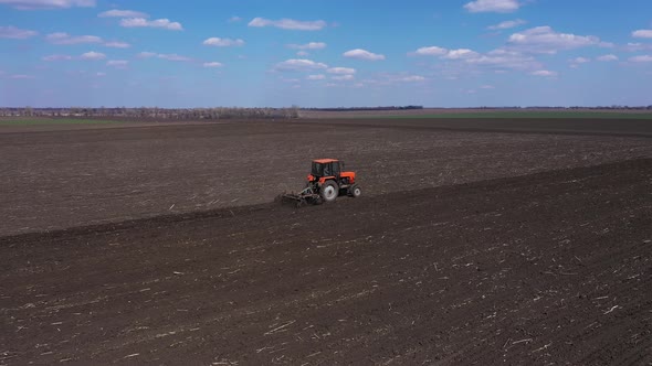 Red Tractor Cultivating Field Aerial View