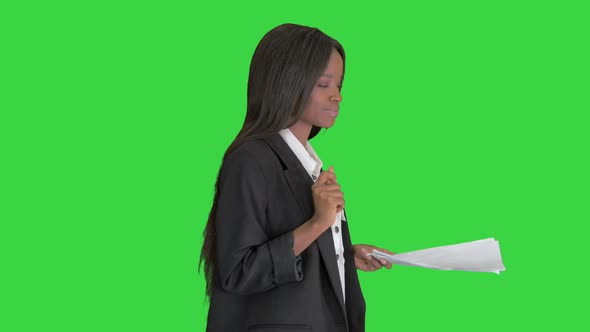 Serious African American Woman Reading Documents While Walking on a Green Screen, Chroma Key.