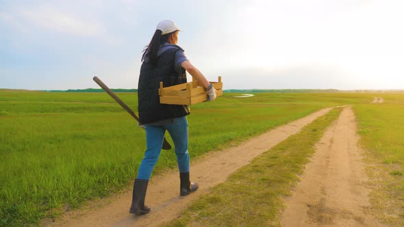 Woman Farmer Holding Shovel in His Hand Walking Across Green Field a Pile of Dirt Soil