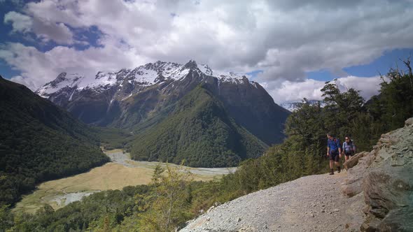 Static, Hikers walk above valley, distant snow capped mountains, Routeburn Track New Zealand