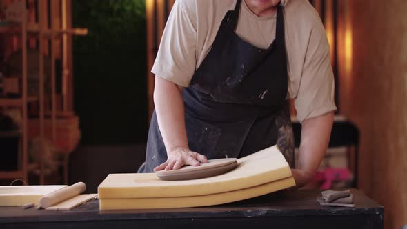 An Eldery Woman Making a Clay Plate Using a Shape on Big Sponge Stand