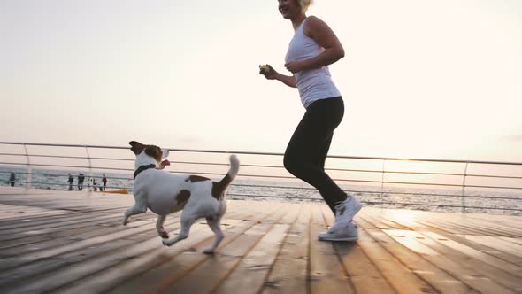 Young Woman Running with Cute Dog Jack Russel Near the Sea Slow Motion