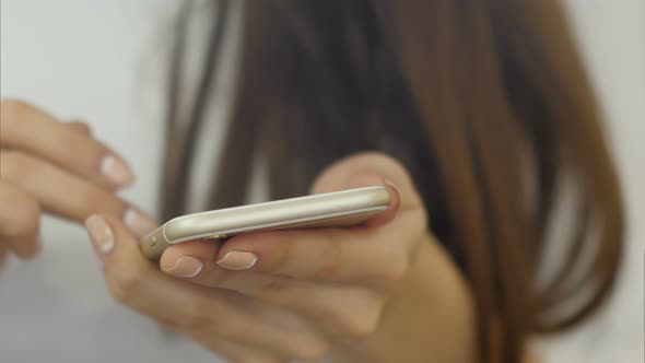 Hands of Young Woman Uses a Smartphone