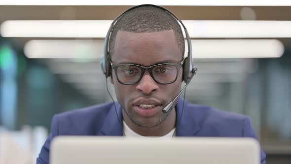 Portrait of African Businessman with Laptop Talking on Headset