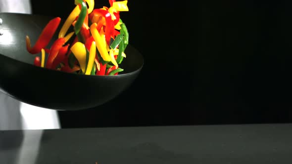 Chef tossing wok of peppers