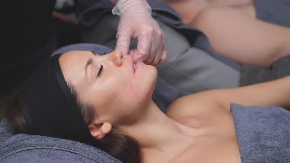 Cosmetologist Makes Buccal Facial Massage for an Attractive Woman. Treatments for Relaxation of