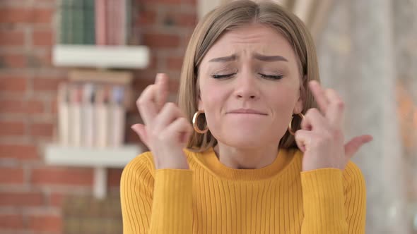 Portrait of Hopeful Young Female Praying with Fingers Crossed 