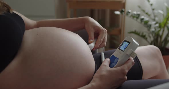 A Young Pregnant Woman Use Pocket Ultrasound Doppler to Check Baby Heart Rate