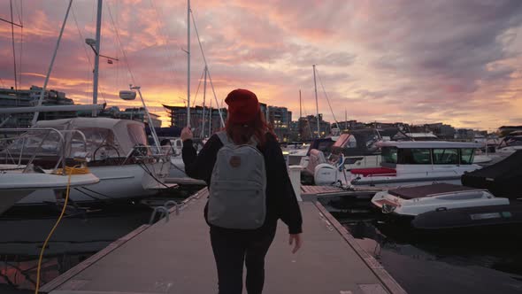 Tourist Women Hipster with a Backpack on the Quay of Ships in the Evening Rear View