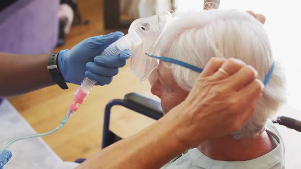 Video of hands of african american male doctor keeping oxygen to caucasian senior woman