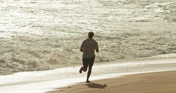Footage of a Man While Running Along the Ocean Coast