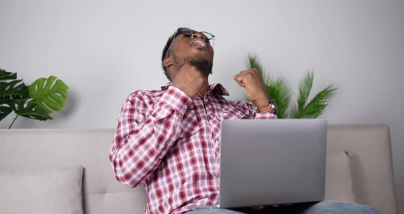 Handsome African man feels happy with successful while use laptop