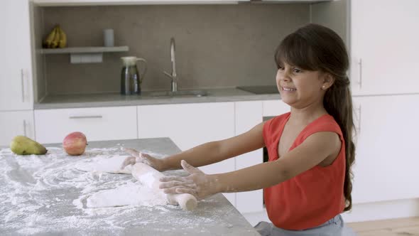 Adorable Little Girl Rolling Dough on Kitchen Table