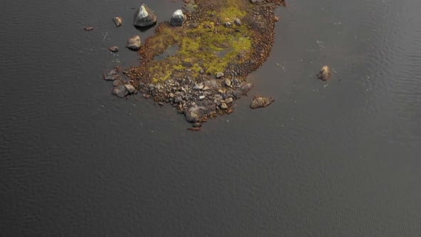 Aerial footage of remote lake in northern Maine flying low over small rocky island.