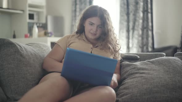 Portrait of Cheerful Plump Woman Using Social Media on Laptop and Smiling. Young Overweight