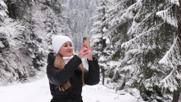 Girl Photographs a Beautiful Winter Forest Walks and Looks at the Snowcovered Nature in January