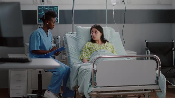 Afroamerican Nurse Discussing with Sick Woman Monitoring Illness Symptom