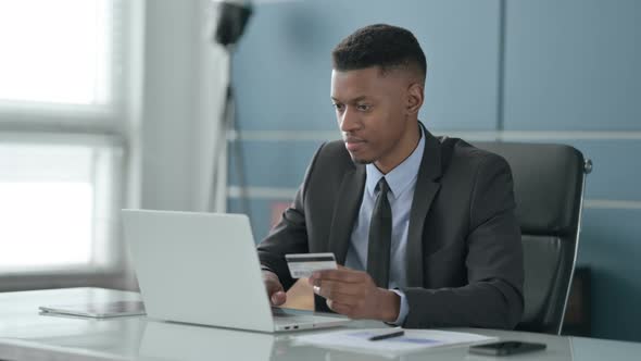 African Businessman making Successful Online Payment on Laptop